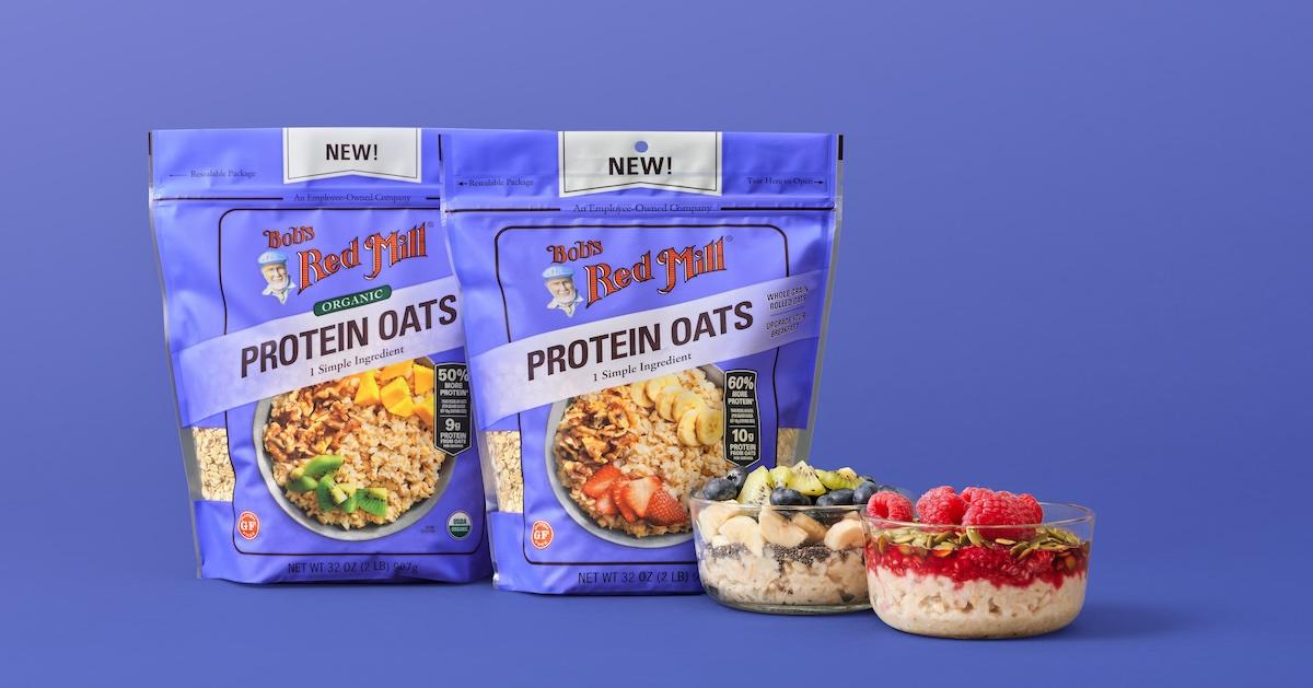 Two purple bags of Bob's Red Mill Protein Oats next to bowls of cereal, on a purple background